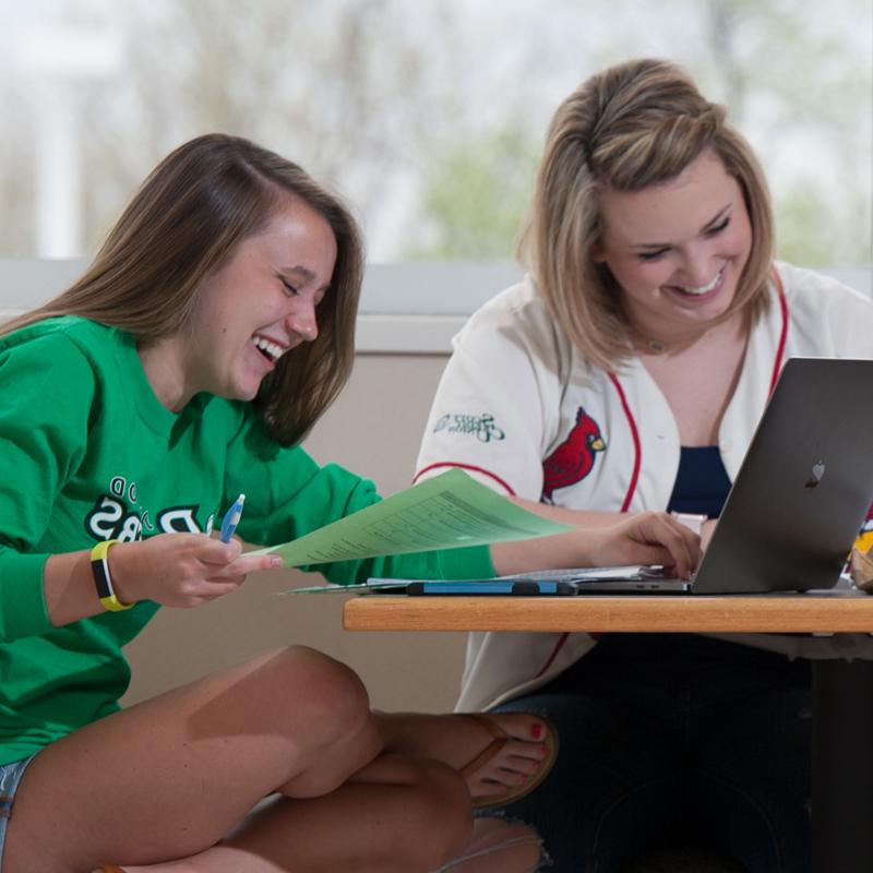 两个女孩在笔记本电脑前微笑
